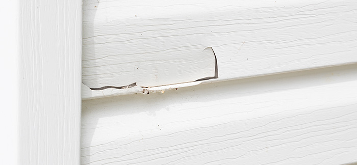 A broken crack in the vinyl siding of a home.
