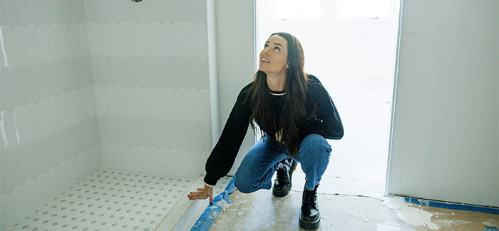 A woman inspecting and repairing subfloor and framing.