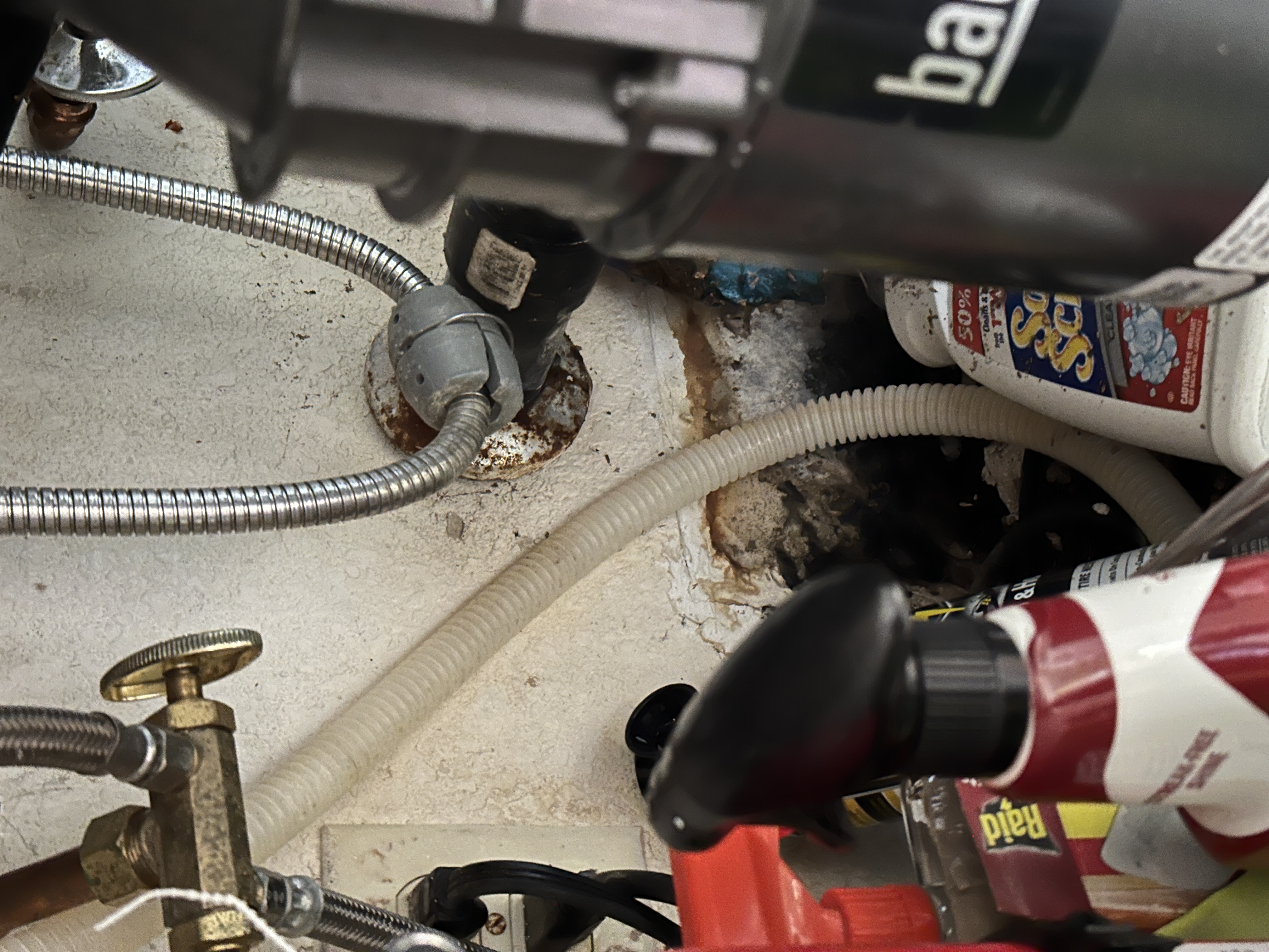 Close-up of black mold growth behind cleaning products under a kitchen sink, indicating water damage in Antioch, CA.