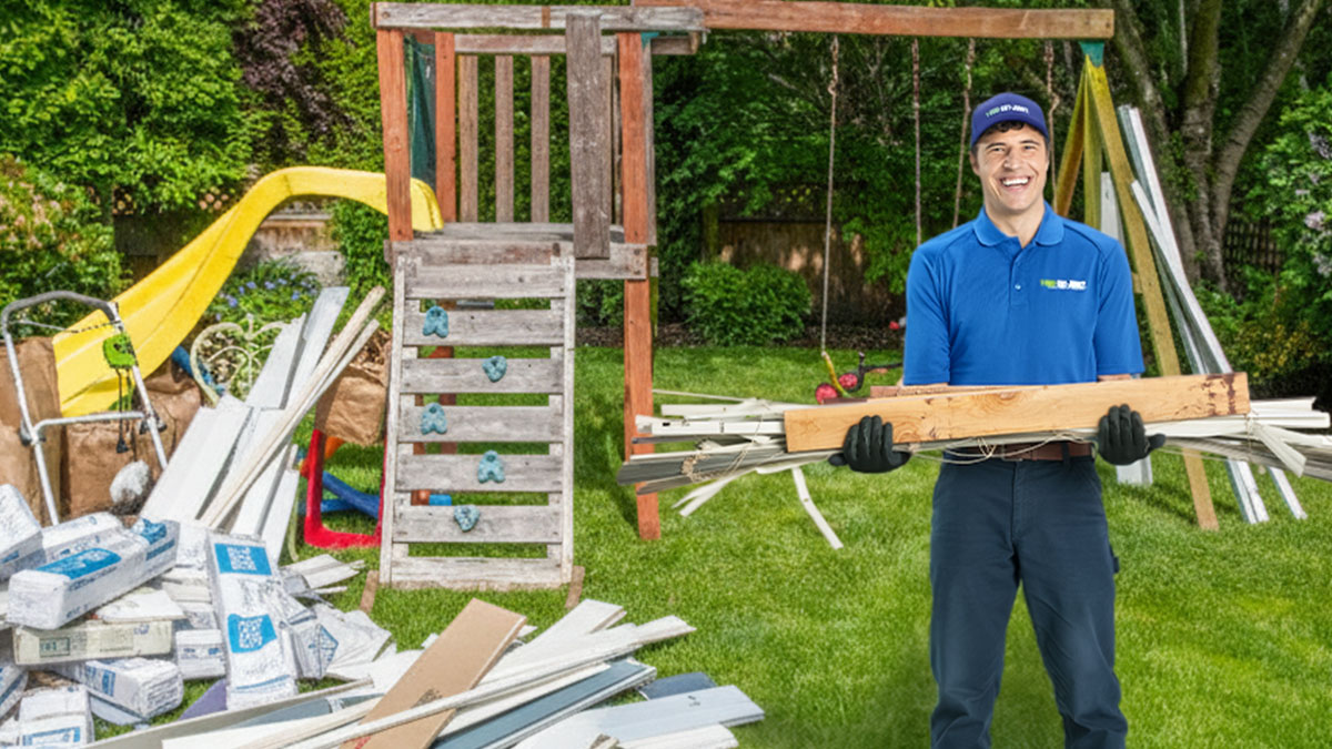 1-800-GOT-JUNK? truck team members removing damaged vinyl siding from a client’s property.