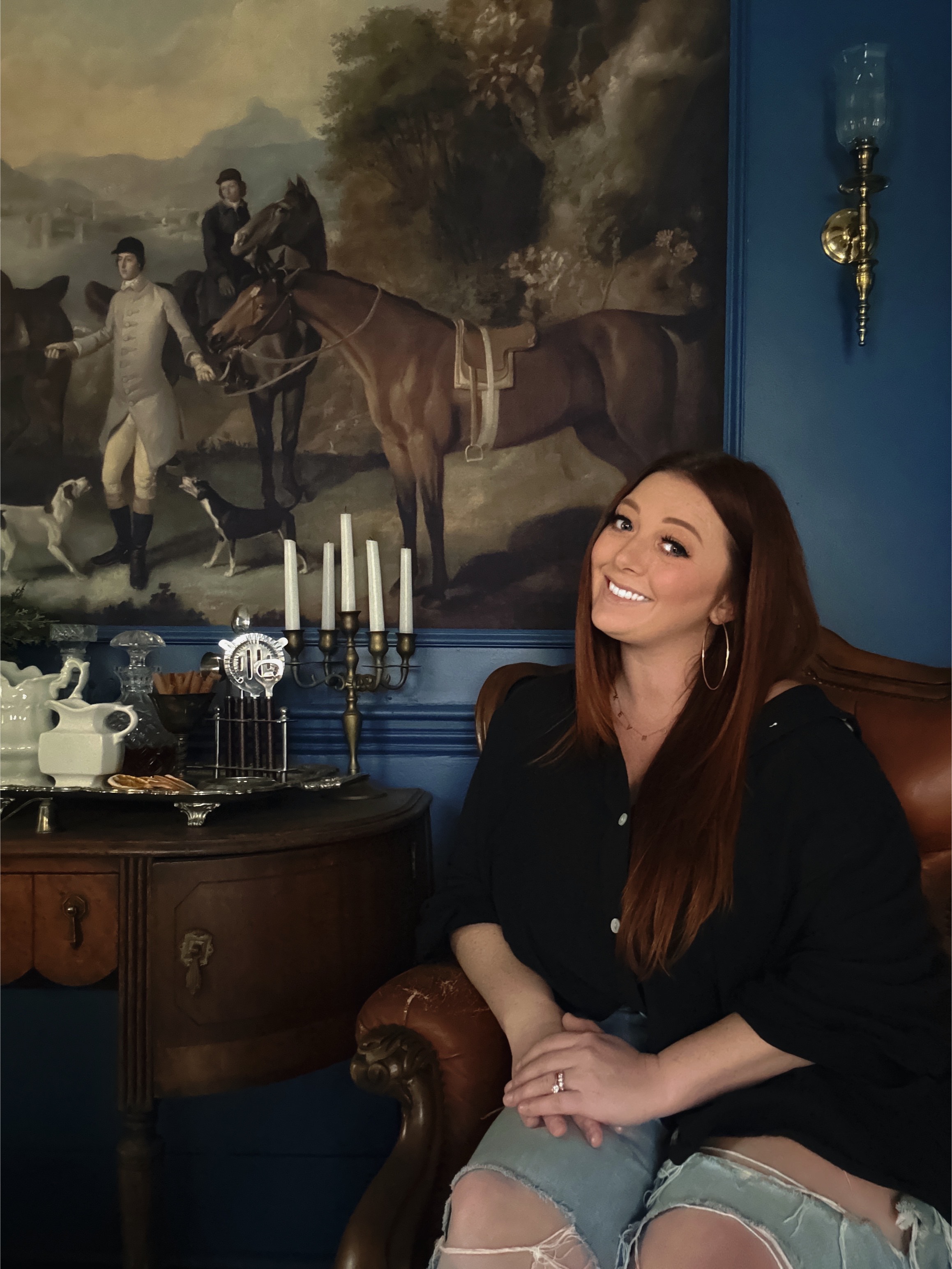 Woman sitting and smiling in front of painting