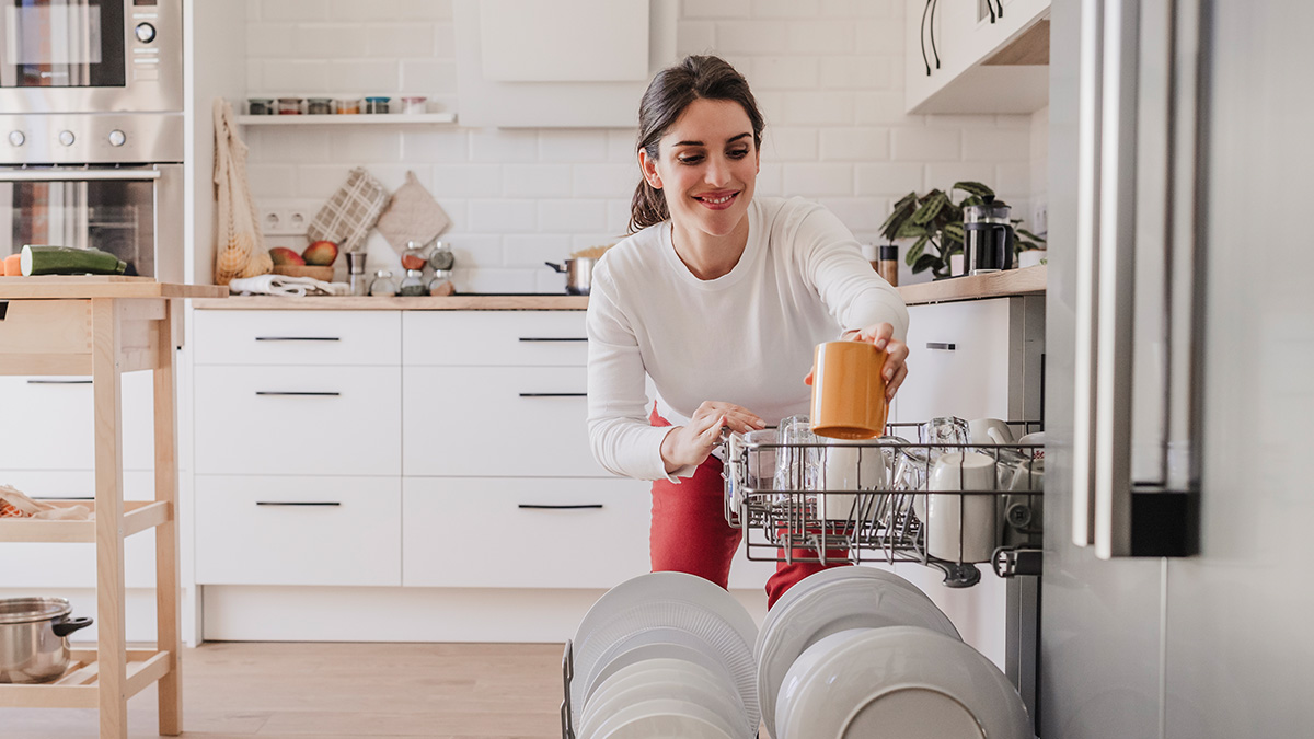 Woman loading dishwasher cleaning kitchen