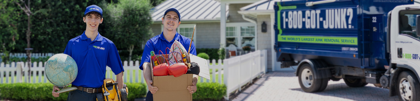 Two 1-800-GOT-JUNK? team members carrying donation items away from junk removal