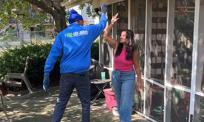 Dina Younis and a 1-800-GOT-JUNK? Truck Team Member high-five each other