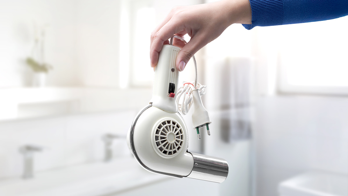 Hand holding an outdated hairdryer in a clean bright space