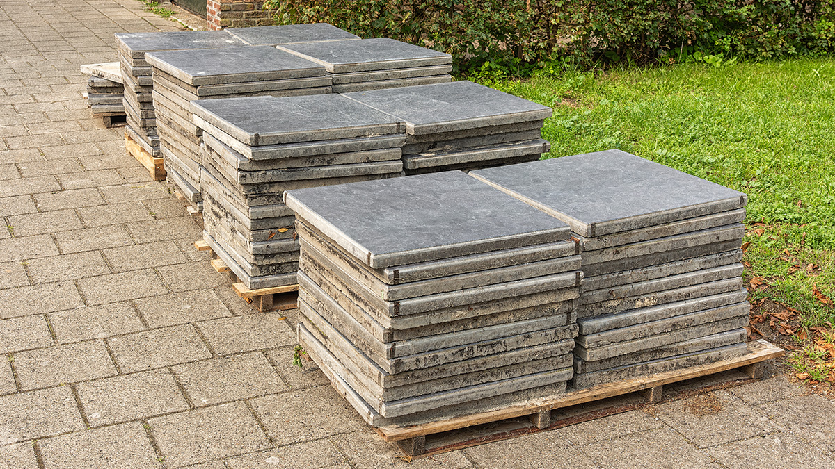 1-800-GOT-JUNK? truck team members disposing of bags filled with ceramic tiles at a recycling center.
