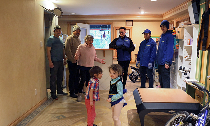 A woman and her family looking shocked and happy with her new decluttered space as 1-800-GOT-JUNK? Founder, Brian Scudamore, and two Truck Team Members smile beside her.