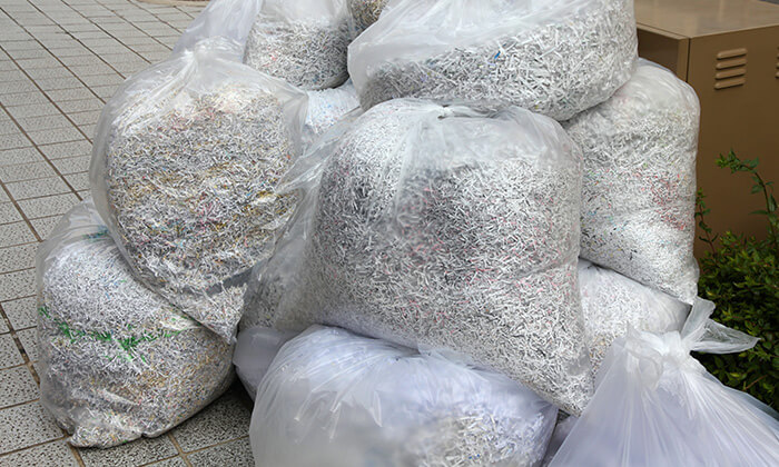 1-800-GOT-JUNK? client dumping shredded paper waste into a large paper bag.